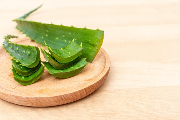 Feuilles fraîches d'aloe vera et tranches d'aloe vera sur fond de bois