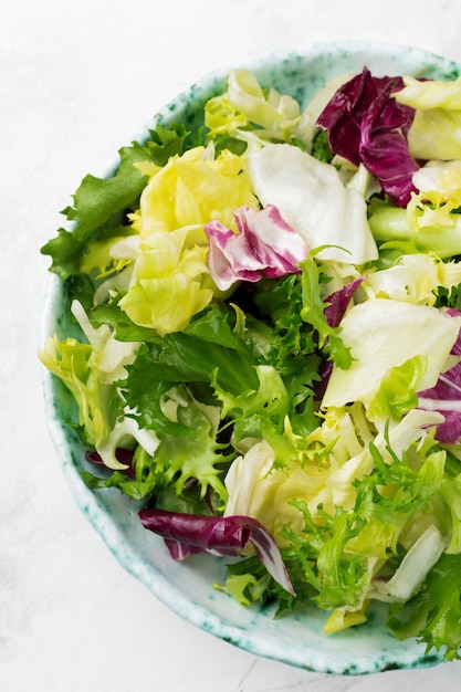 Feuilles fraîches de salade différente dans une assiette en céramique