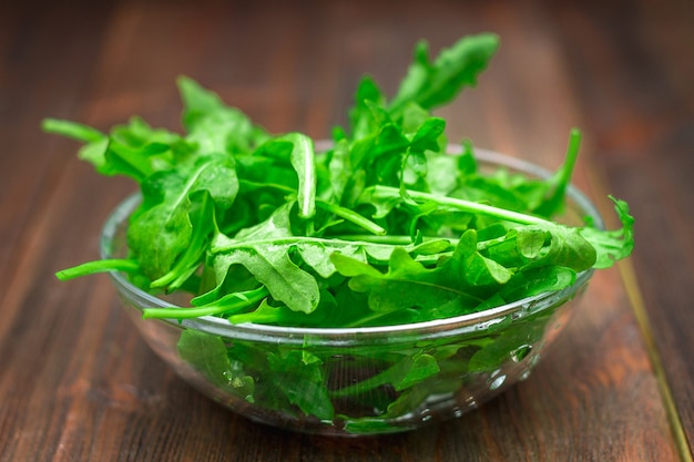 Feuilles juteuses fraîches de roquette sur une table en bois marron.