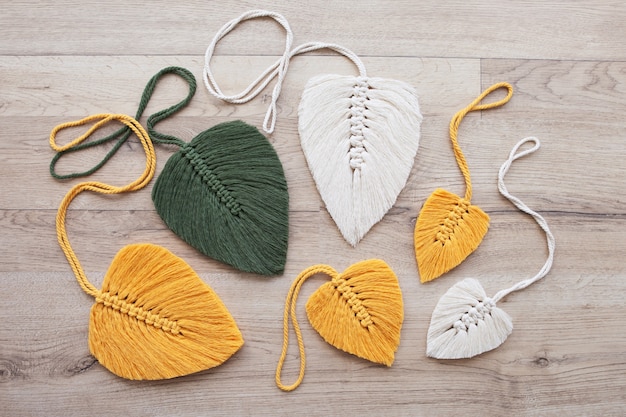 Feuilles de macramé de couleur jaune, verte et naturelle sur le fond en bois. Macramé de décoration en corde de coton pour rendre votre maison plus confortable et unique.