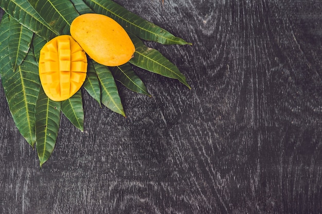 Photo feuilles de mangue et mangue sur une vieille table en bois