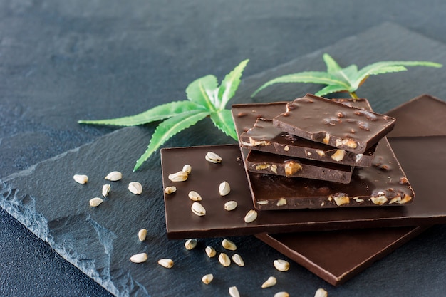 Feuilles de marijuana et chocolat noir sur fond noir.