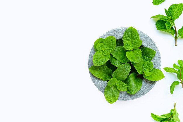 Feuilles de menthe dans un mortier de pierre sur fond blanc Vue de dessus