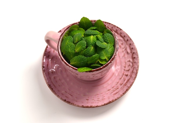 Feuilles de menthe dans une tasse isolée sur fond blanc.