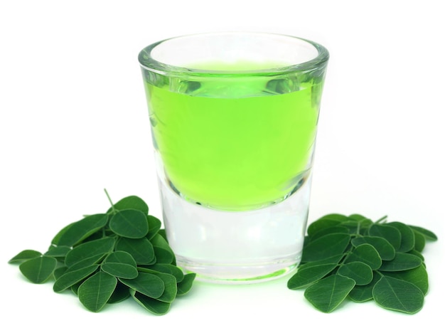 Feuilles de Moringa avec extrait dans un verre sur fond blanc