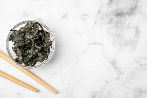 Feuilles de nori hachées avec des baguettes sur une table en marbre blanc mise à plat Espace pour le texte