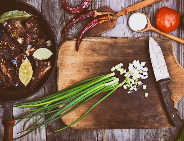 Feuilles d&#39;oignon vert sur un plateau de cuisine avec un couteau