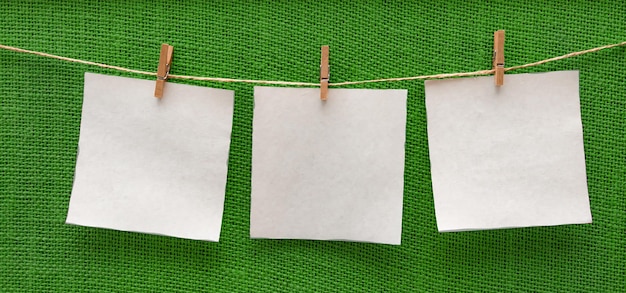 feuilles de papier blanches suspendues isolées sur une planche greenbeige sur des pinces à linge maquette d'espace libre