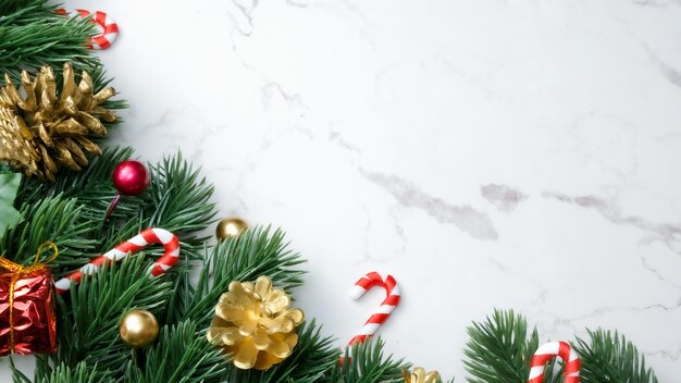 Feuilles de pin vert, décorations de Noël rouges et cannes de bonbon sur fond de marbre blanc, décorations de Noël de couleur rouge vif. Concept de Noël simple et créatif.