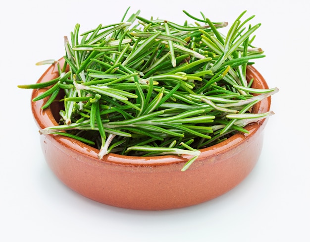 Feuilles de romarin vert fraîchement coupées (Rosmarinus officinalis) dans un bol en argile. Apparence rustique Ingrédient isolé de la cuisine méditerranéenne et du remède maison curatif.