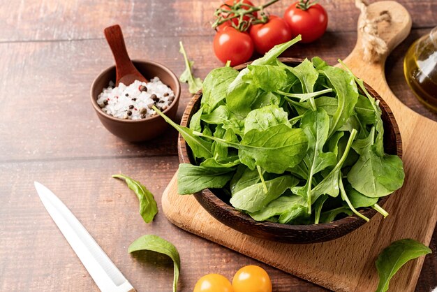 Feuilles de roquette fraîches dans un bol brun avec des légumes frais