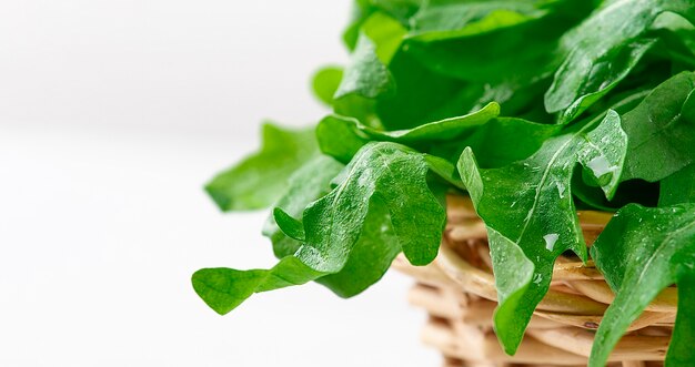 Feuilles de roquette fraîches dans un panier sur fond blanc