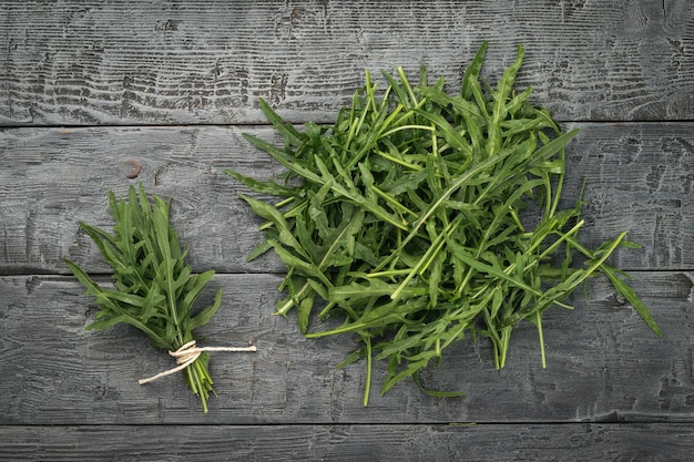 Feuilles de roquette se trouvant dans un tas et un tas sur un fond en bois Mise à plat