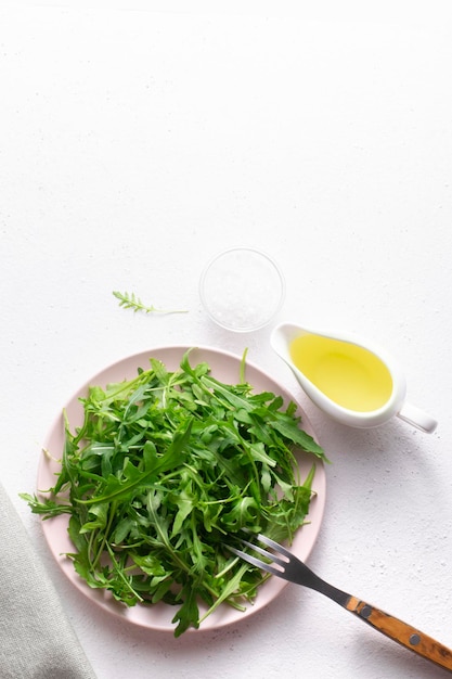 Feuilles de roquette XAFresh avec de l'huile et du sel dans une assiette sur une vue de dessus de fond blanc