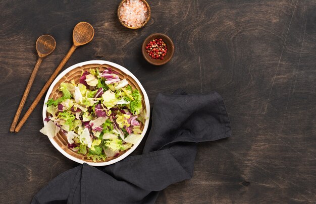 Feuilles de salade de mélange de printemps vert frais dans une passoire en bois sur fond rustique en bois. Mise au point sélective.