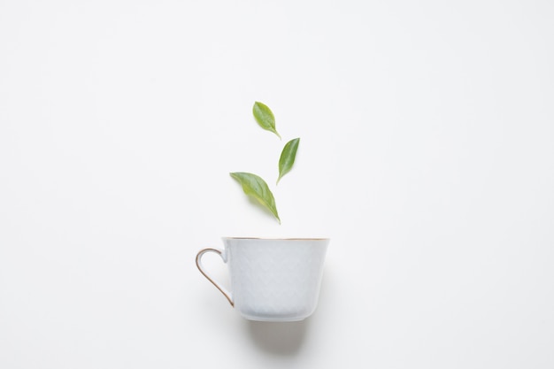 Photo feuilles de thé au citron sur la tasse en porcelaine contre fond blanc