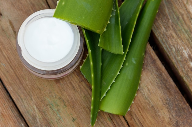 Feuilles vertes d'aloe vera et crème hydratante sur fond de bois rustique