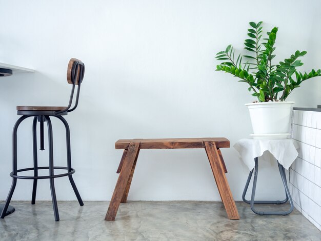 Feuilles vertes en pot blanc et banc en bois