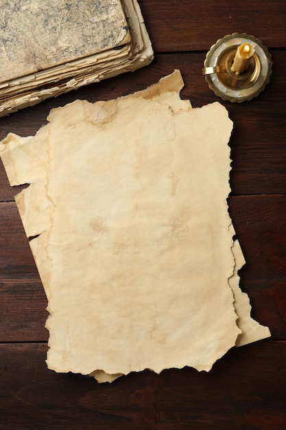 Des feuilles de vieux papiers en parchemin, des livres vintage et des bougies sur une table en bois.