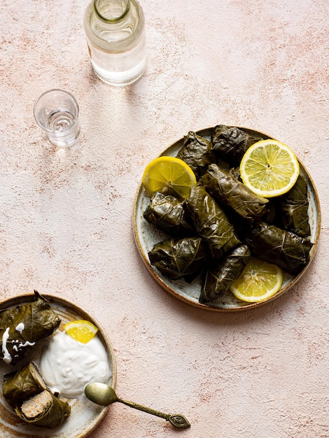 Feuilles de vigne avec dolma de viande et moonshine de raisin sur fond beige