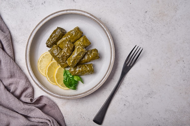 Feuilles de vigne farcies Dolma avec riz et viande dans une assiette lumineuse avec fourchette noire et dessus de serviette en lin