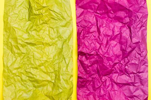 Des feuilles violettes et jaunes froissées de papier de couleur sur un fond de carton jaune. Fond hétéroclite de texture. Vue de dessus. Espace de copie