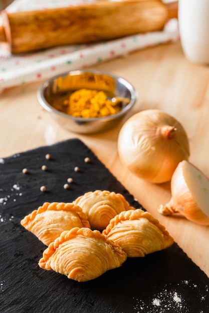 Feuilleté au curry sur une assiette sombre et ingrédients