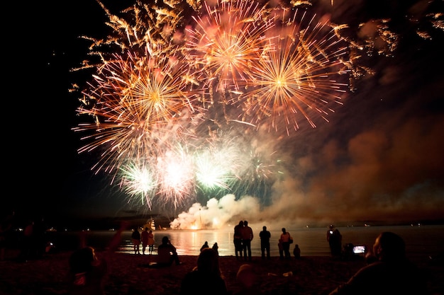 Feux d'artifice de vacances au-dessus de l'eau avec réflexion sur le fond de ciel noir