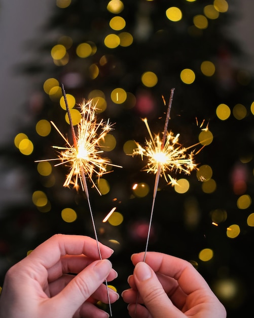 Feux de Bengale dans les mains des femmes sur le fond de l'arbre de Noël Bonne année