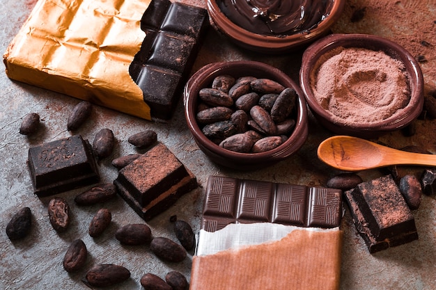 Photo fèves de cacao et poudre avec des morceaux de barre de chocolat sur la table