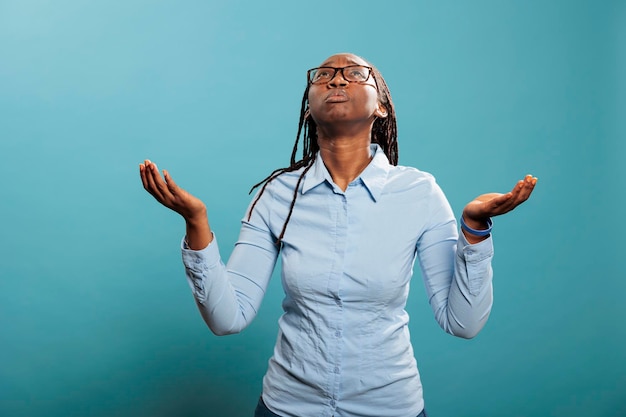 Fidèle femme afro-américaine avec des paumes face au ciel implorant et suppliant d'avoir ses péchés pardonnés. Jeune religieux et spirituel priant pour un monde meilleur et qui pardonne. Prise de vue en studio