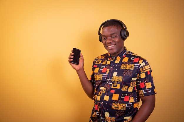 Fier jeune garçon noir écoutant de la musique de ses écouteurs avec un sourire Studio photo