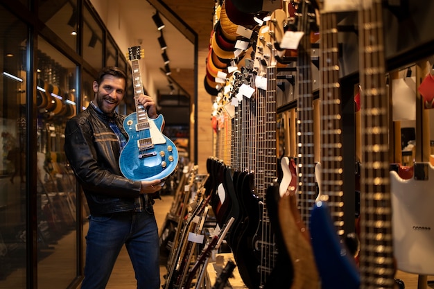 Fier jeune musicien rocker en cuir jacked holding electric guitar in music shop.