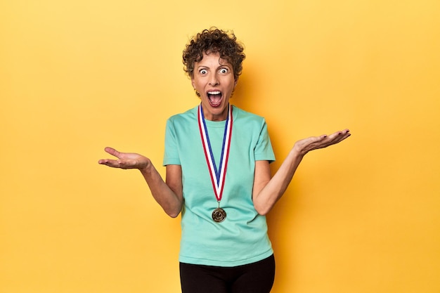 Photo fière sportive affichant sa médaille gagnante sur fond jaune de studio