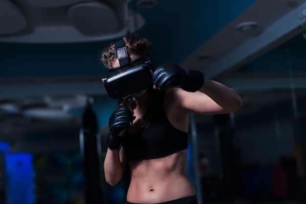 Fighter boxer fit girl punching in VR lunettes portant des gants de boxe dans la formation Futuriste de jeu