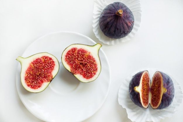 Figues coupées et entières sur une assiette Sur un fond blanc Mise à plat Vue de dessus Copier l'espace