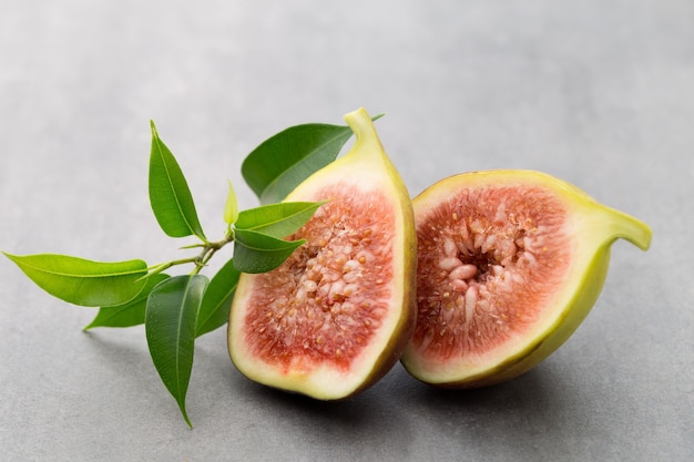 Figues entières et une figue coupée en deux sur une table grise