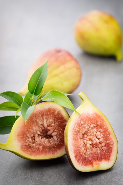 Figues entières et une figue coupée en deux sur une table grise