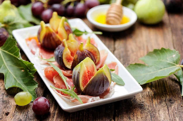 Figues fraîches au jambon sur une plaque blanche