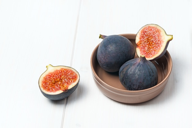 Figues fraîches dans un bol en céramique sur une table en bois blanc