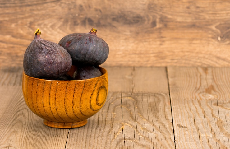 Photo figues fraîches entières dans une assiette en bois