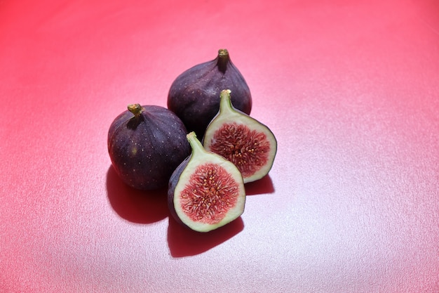 Figues fraîches mûres coupées en deux sur fond rouge Fruits d'été frais.