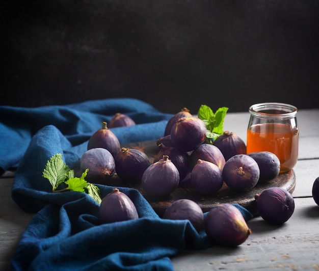 Figues fraîches sur une table en bois sombre avec du miel et de la menthe