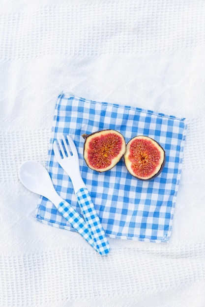 Des figues mûres biologiques fraîches coupées en deux parties reposent sur une serviette à carreaux bleus Préparation des figues pour faire de la confiture Plat d'automne Espace libre pour le texte