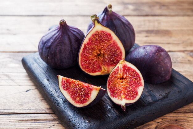 Figues mûres entières et coupées sur une planche à découper en bois. Mise au point sélective Espace copie.