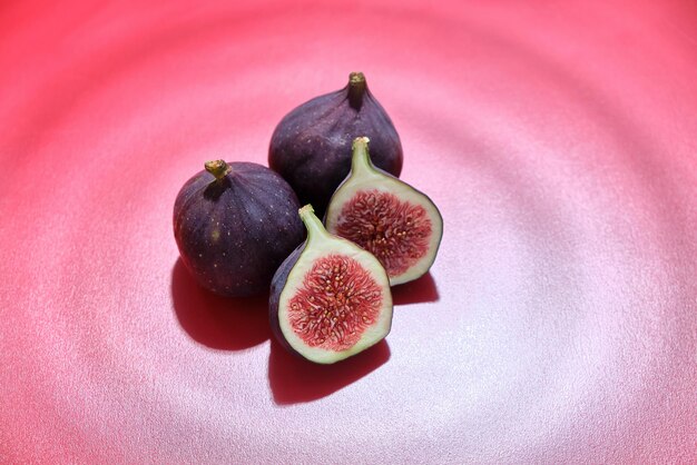 Figues mûres fraîches coupées en deux sur fond rouge avec l'effet des vagues d'eau. Fruits frais d'été.