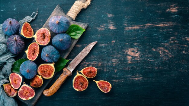 Figues sur une planche de bois Couper les figues Sur un fond sombre Espace libre pour le texte Vue de dessus