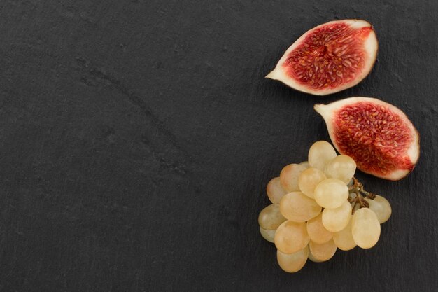 Figues et raisins mûrs frais sur fond sombre, vue de dessus avec espace de copie.