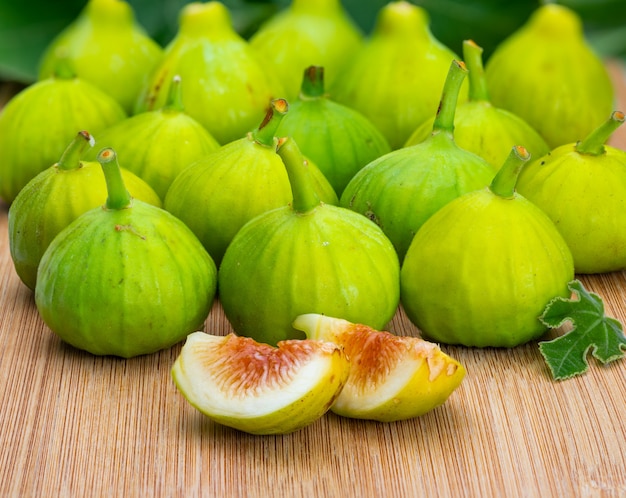 Figues vertes entières et coupées, avec des feuilles de vigne.