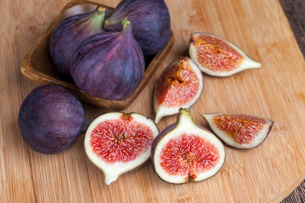 Figues violettes mûres sur une table en bois, figues mûres avec pulpe rouge et beaucoup de graines